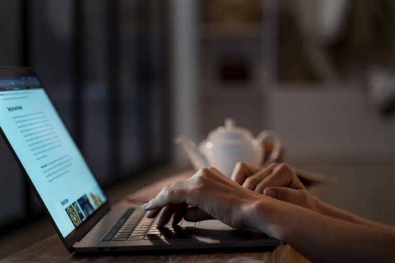 A person focused on typing on a laptop computer, with hands positioned over the keyboard.